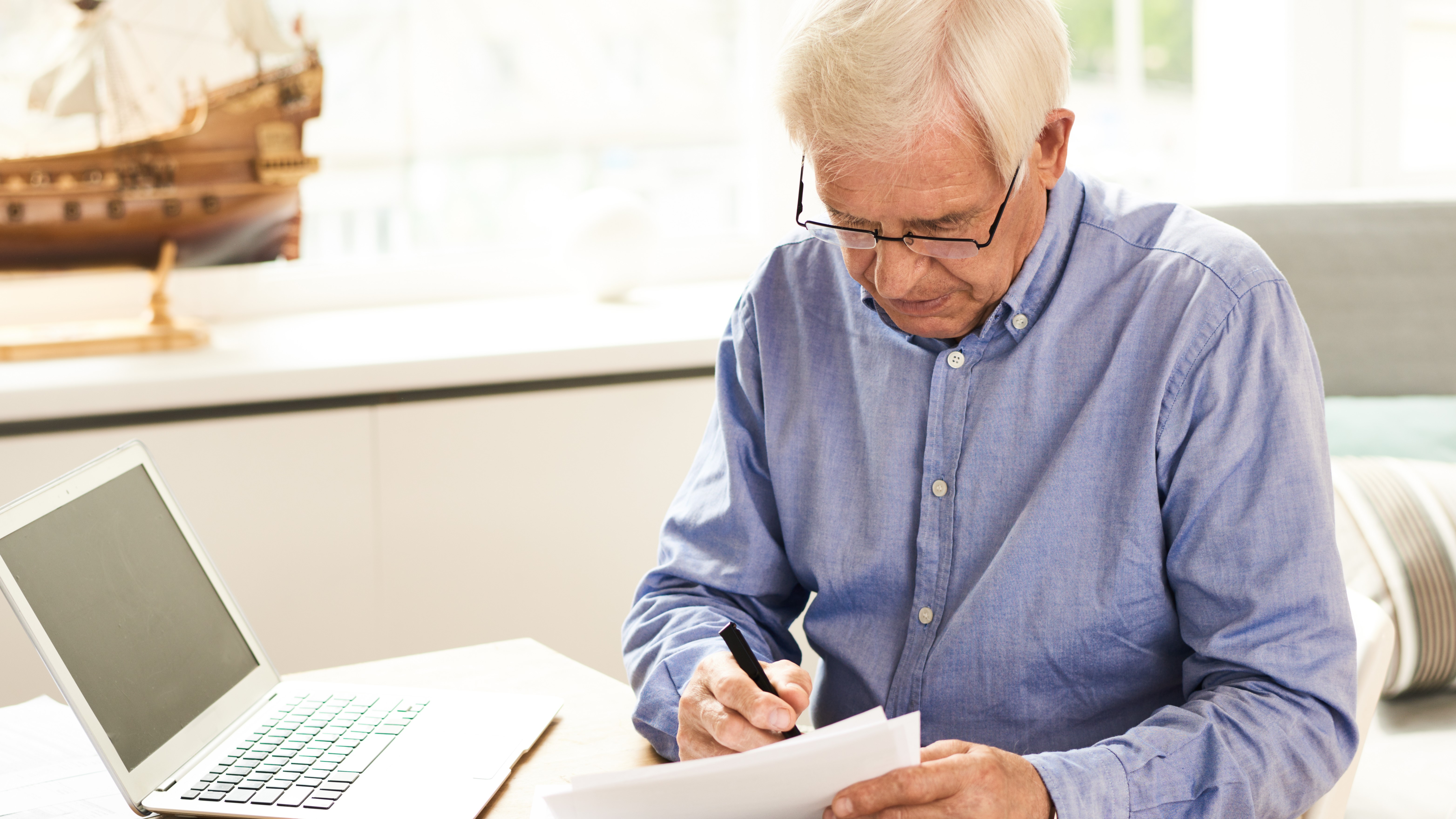 пожилой мужчина. пишут мужчины старше. человек за столом. Man writing. пожилой мужчина пишет книгу лицом вперед.